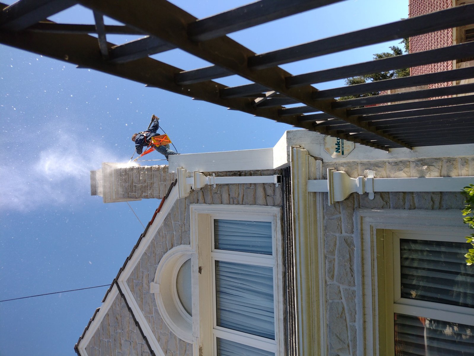 Operario realizando descenso vertical para hidrolavado de cornisa en altura en Mar del Plata