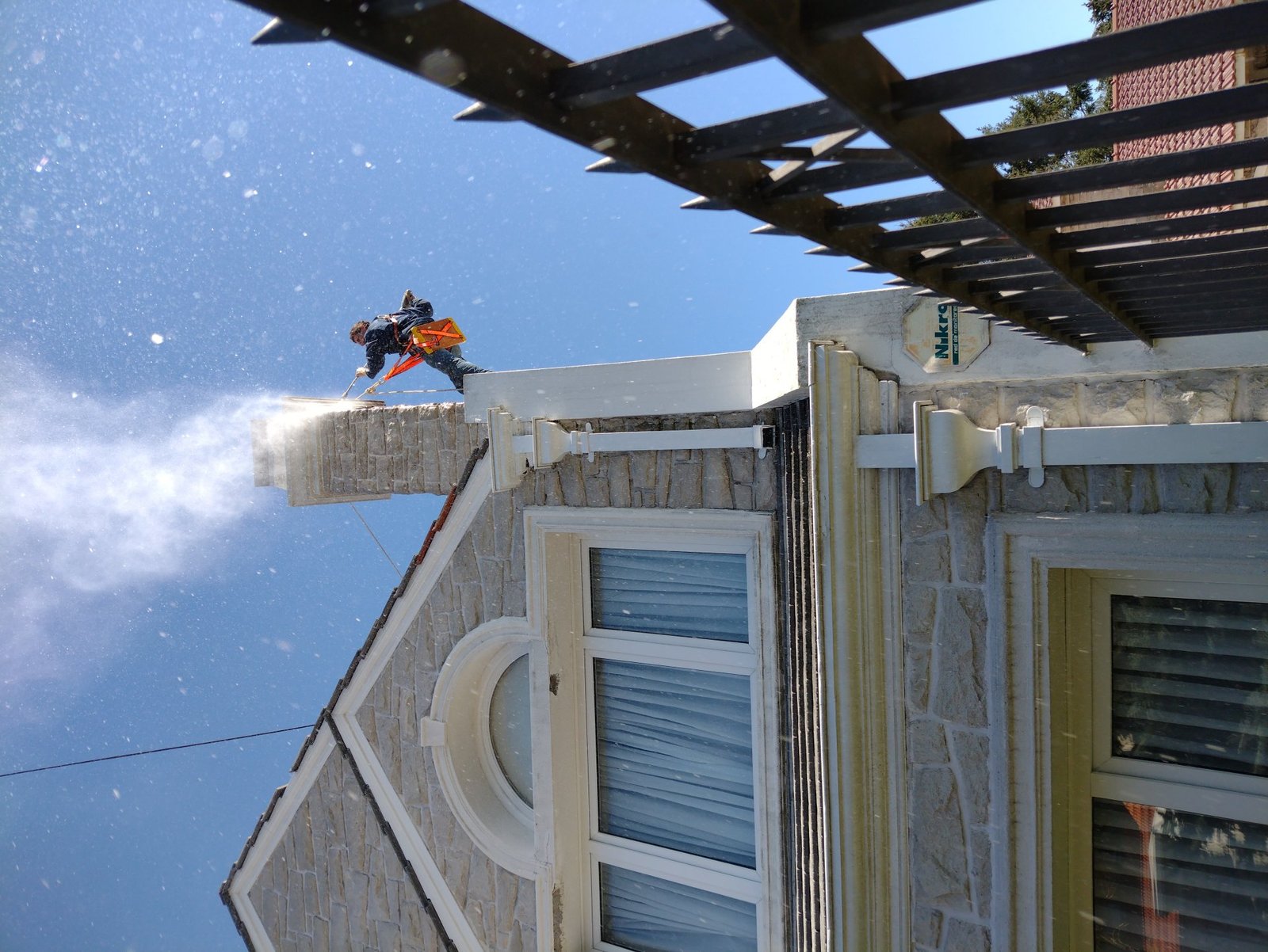 Operario en rappel hidrolavando cornisa de un edificio en Mar del Plata